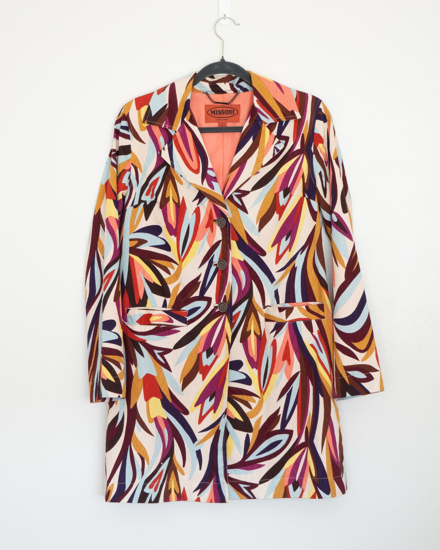 Blazer Missoni con estampado gráfico en tonos cálidos y contrastes marcados.  Composición de color y movimiento que construye una pieza con identidad inmediata. Corte recto y largo medio que permite usarlo tanto como blazer protagonista o como capa liviana.